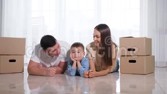 可爱的家庭和可爱的小儿子躺在新房子的地板上视频的预览图