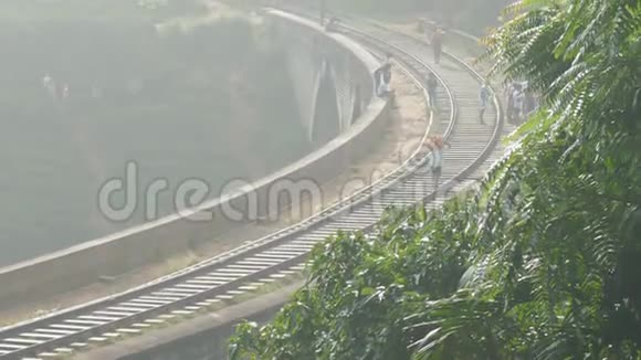 人们走在位于丛林老桥的铁路轨道上视频的预览图