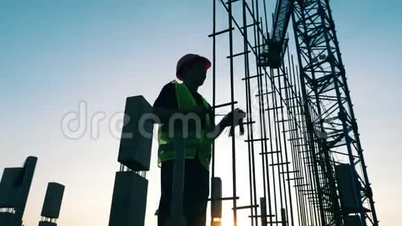 一名工程师在一个建筑工地上用金属杆工作视频的预览图