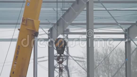 起重机和钩子钩一鹤黄色建筑吊臂用钢钩跨越施工现场视频的预览图