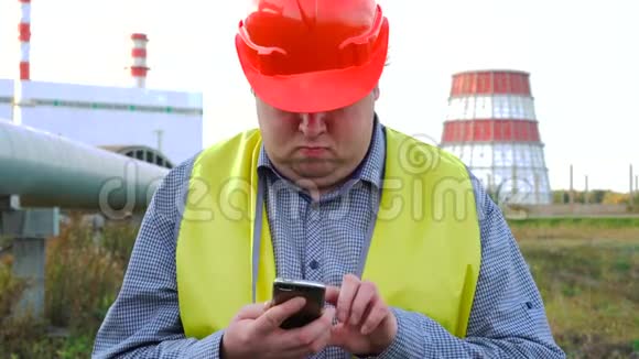 工作人员工程师或电工在电站前用智能手机直接看摄像机视频的预览图