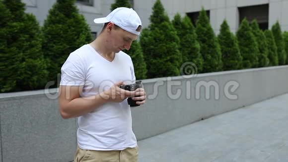 一个戴白色帽子的年轻人手里拿着相机视频的预览图