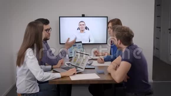 移动应用开发团队正在与办公室会议室的专家进行视频通话视频的预览图