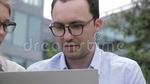 一对聪明的夫妇拿着笔记本电脑坐在街上视频的预览图
