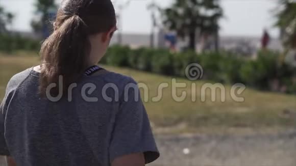 穿灰色T恤的女孩正在公园里散步后景视频的预览图