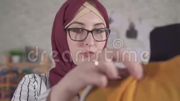 年轻的穆斯林女性时装设计师在她的展厅里调整一件装在人体模型上的衣服视频的预览图