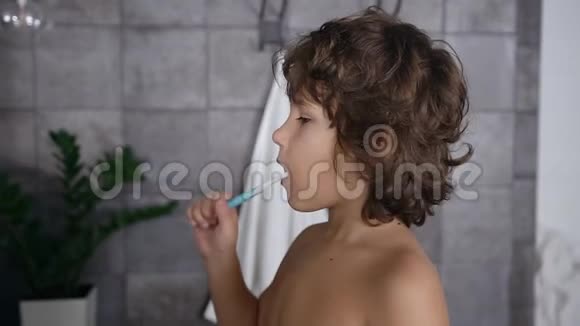 在浴室里用牙刷刷牙的可爱黑发小男孩的侧景视频的预览图