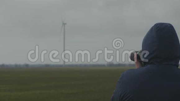 在一个多云的日子里一个职业摄影师在一个野外拍摄旋转风力发电机的照片视频的预览图
