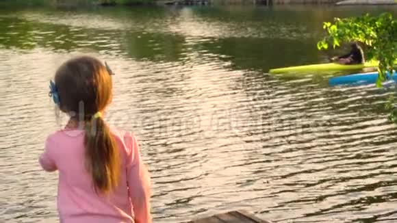 小女孩看着两个男人在河里皮划艇视频的预览图