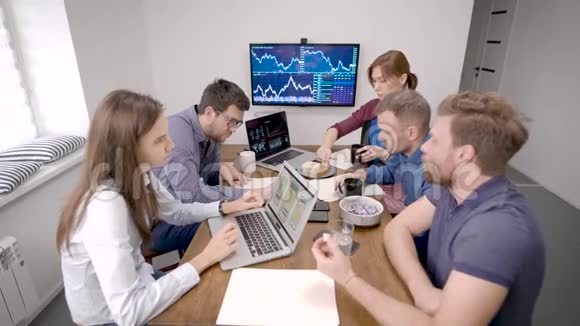一群专家正在办公室里工作坐在一张大桌子上喝咖啡休息视频的预览图