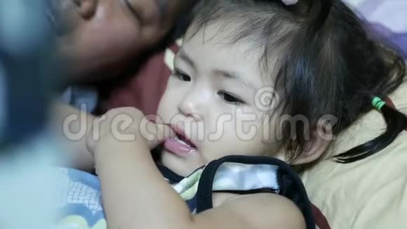 小亚洲女婴2岁拇指在嘴里而母亲正在为她读一个睡前故事视频的预览图
