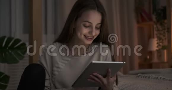 深夜在卧室里使用数码平板电脑的快乐少女视频的预览图