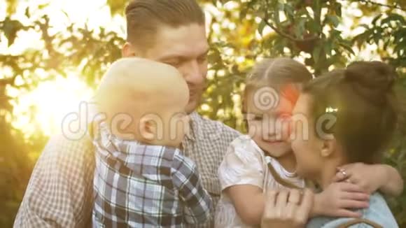 阳光明媚的一天快乐的父亲在公园里拥抱他的家人妈妈爸爸和孩子们在日落时笑着拥抱视频的预览图