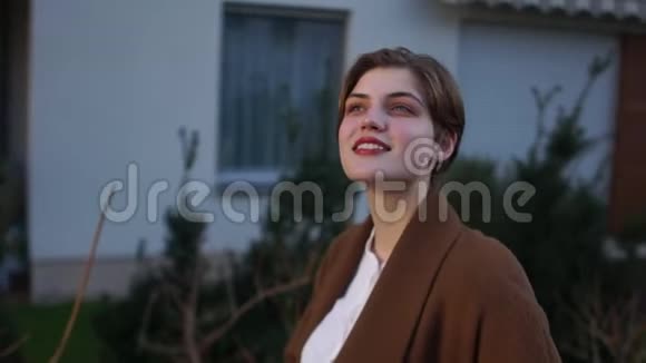 城市肖像一个美丽的年轻女孩的短发和棕色外套快乐的女人视频的预览图