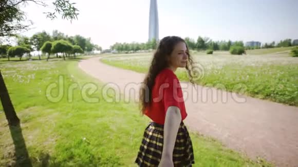 可爱的女孩拉着那家伙的手年轻漂亮的女人走在田野上穿红色T恤的快乐女士视频的预览图