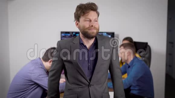 快乐的首席执行官经理正微笑着站在办公室的镜头前员工在他身后开会视频的预览图