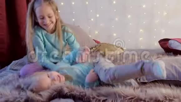 姐姐在家里的床上和妹妹在卧室里玩逗着妹妹视频的预览图