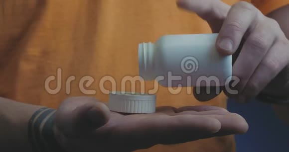 成年男子将止痛药从瓶子里倒入瓶盖手里拿着服药保健药房视频的预览图
