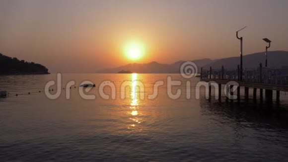 金色的太阳和游船漂浮在山上的轮廓而早晨的日出美丽的景色明亮的日落大海视频的预览图