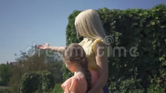金发母亲和她的小女儿一起在夏天的公园里度过女人和女孩都很欣赏视频的预览图