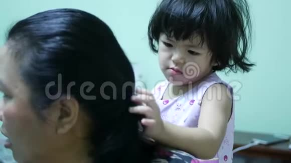 小亚洲女孩给她阿姨做头发通过学习为别人做事情来发展孩子视频的预览图