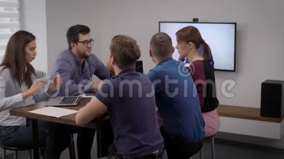 年轻人坐在会议室的桌子旁与公司老板进行视频会议视频的预览图