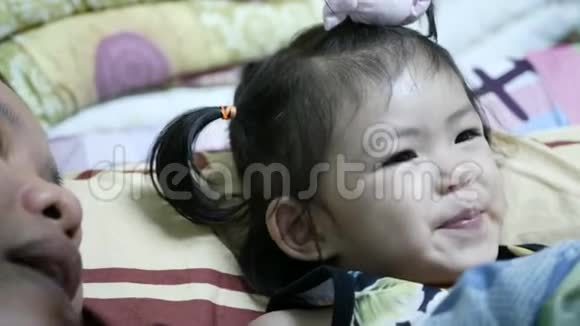 小亚裔泰裔2岁的小女孩在她睡觉前跟着妈妈大声重复一本书中的词汇视频的预览图