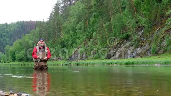 去钓鱼一个穿着红色衣服的有经验的渔夫站在水里山河一个留着胡子的人看起来像萨视频的预览图