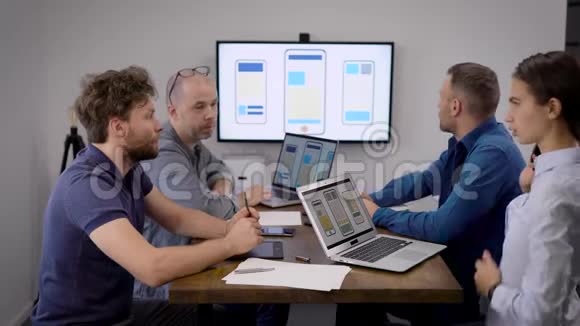 4个人坐在手机应用开发公司办公室的会议室里视频的预览图