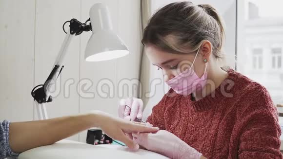 穿粉色面具的女指甲技师在美容院做美甲客户视频的预览图