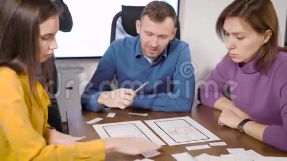 男人和两个女人正在为智能手机开发新的应用程序在办公室里坐在桌旁填写文件视频的预览图
