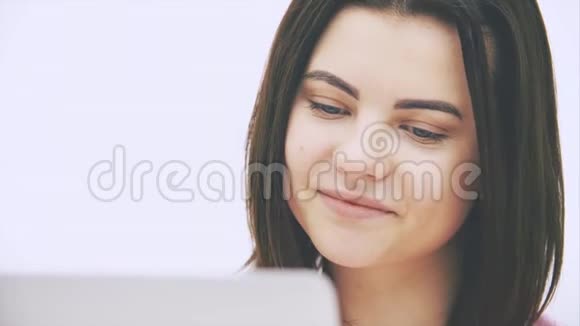 可爱的白种人黑发女孩带着笔记本电脑在互联网上冲浪微笑眉毛点头视频的预览图