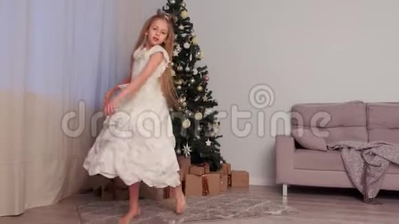 家中圣诞树附近穿着白色裙子跳舞的胖女孩视频的预览图