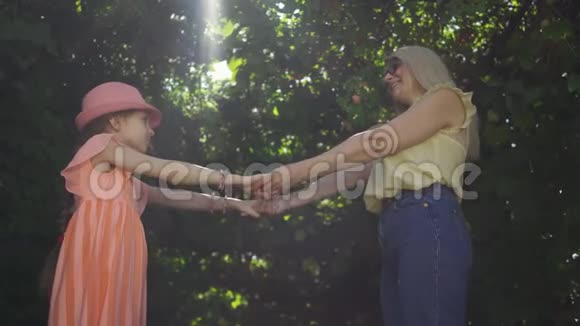 女人和女孩牵着手漂亮的金发母亲和女儿花时间在夏天的花园或公园里视频的预览图