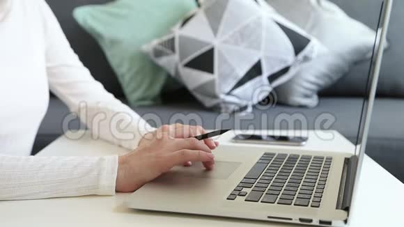 自由职业者在家里用笔记本电脑工作女性手拿铅笔视频的预览图