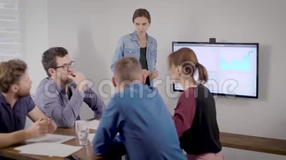 女人正在办公室里参加商务会议她的同事们坐在桌子旁听着看着视频的预览图