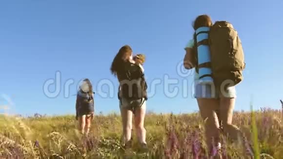 旅行者带着背包穿过草地妈妈和女儿一个小婴儿带着背包穿越田野视频的预览图
