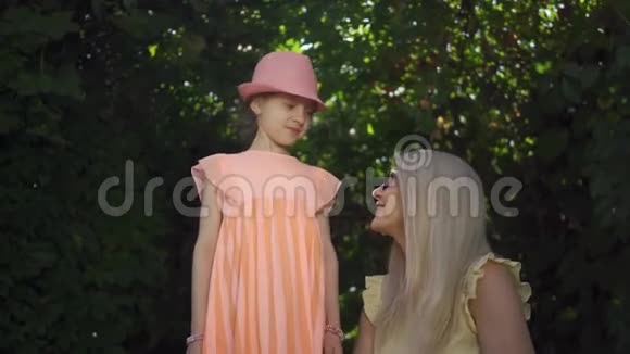 肖像金发母亲和她的女儿在夏天的花园里用手指看相机形成了心形视频的预览图