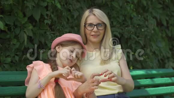 成熟的金发母亲戴着眼镜女儿用手指看着坐在镜头上的镜头形成了心形视频的预览图