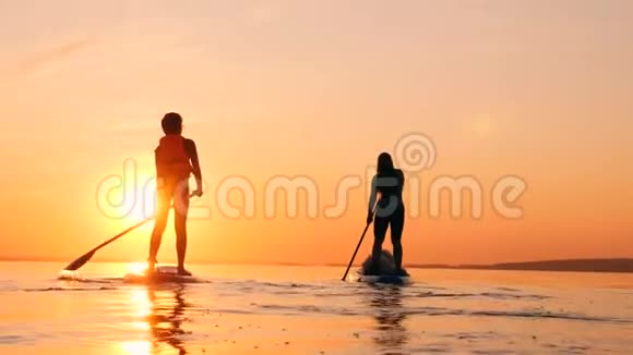 日落时分一个男孩和一个母亲在划桨视频的预览图
