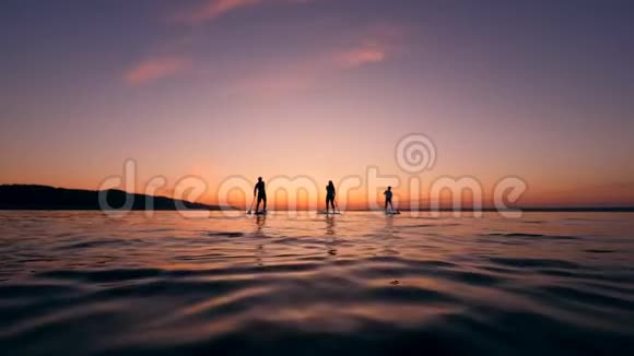 日落的海水和一群年轻朋友在划桨视频的预览图