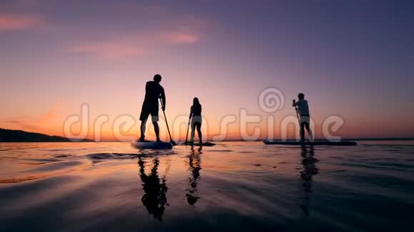 日落时分年轻人划艇的背面景色视频的预览图