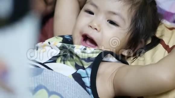 2岁的亚洲小女孩喜欢听妈妈朗读一本书中的睡前故事视频的预览图