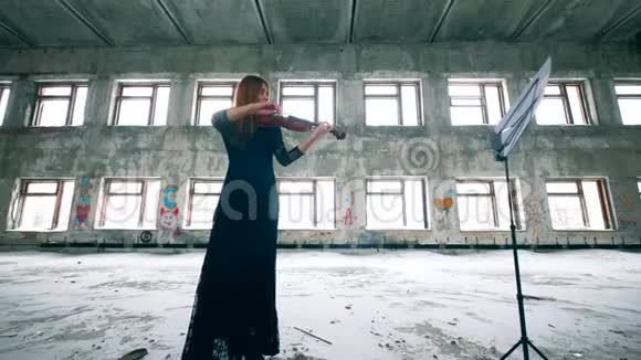 一个女人在破楼里用音符拉小提琴视频的预览图