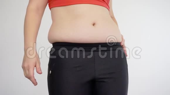 穿着运动服的超重女人捏着她的腹部脂肪纤维素和暴饮暴食视频的预览图