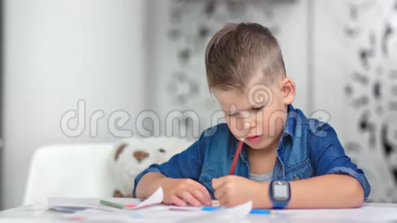 时尚自信的男孩在课桌上画纸周围是教室白色的内部视频的预览图