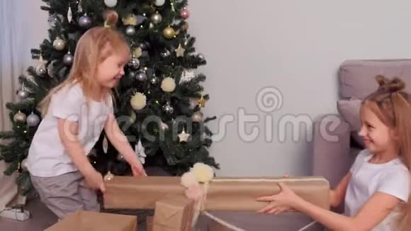 姐妹在家中圣诞树附近分享礼物和礼物的盒子视频的预览图
