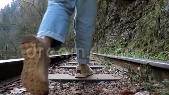 穿牛仔布的年轻女子独自走在火车轨道上视频的预览图