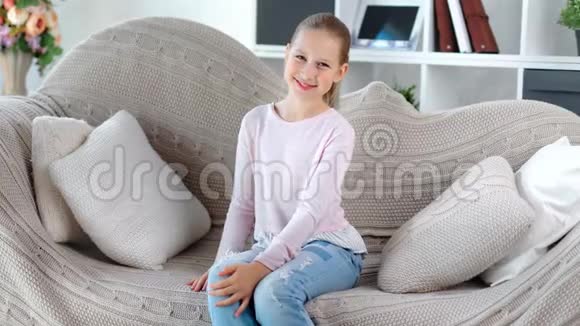 微笑迷人的欧洲女孩子坐在沙发上看着摄像机视频的预览图