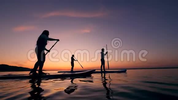 年轻人骑着桨板穿过落日湖视频的预览图
